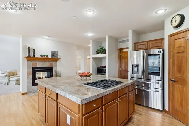 a kitchen that has a kitchen island wooden cabinets and stainless steel appliances