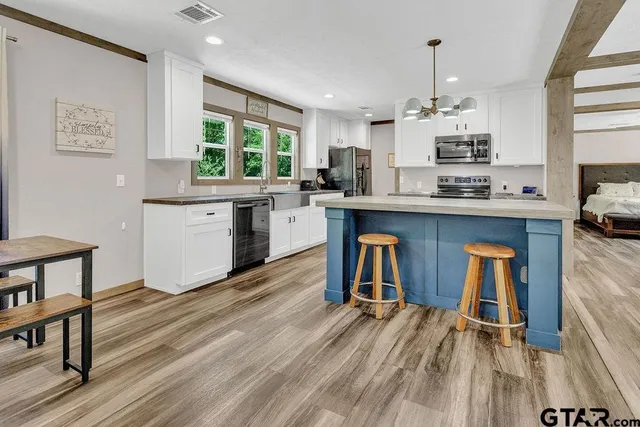 a kitchen with stainless steel appliances granite countertop a table chairs stove a sink dishwasher and cabinets with wooden floor