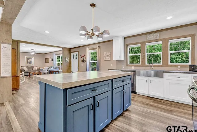 a large kitchen with kitchen island a large counter space a sink appliances and a large window