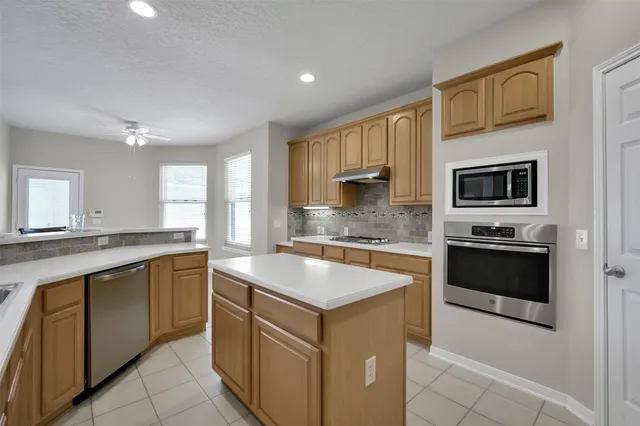 a kitchen with stainless steel appliances granite countertop a stove top oven a sink and dishwasher