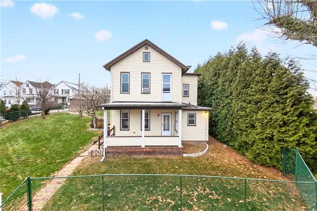 a view of a white house with a yard table and chairs