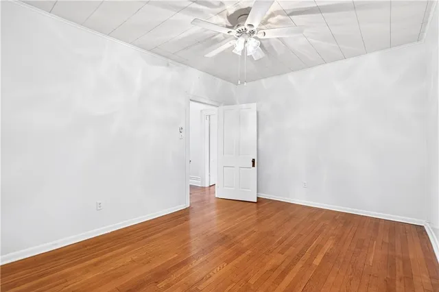 an empty room with wooden floor and fan
