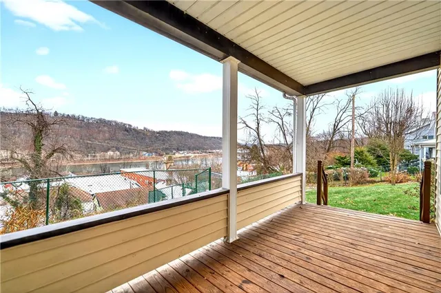 a view of roof deck with wooden floor and fence next to a yard