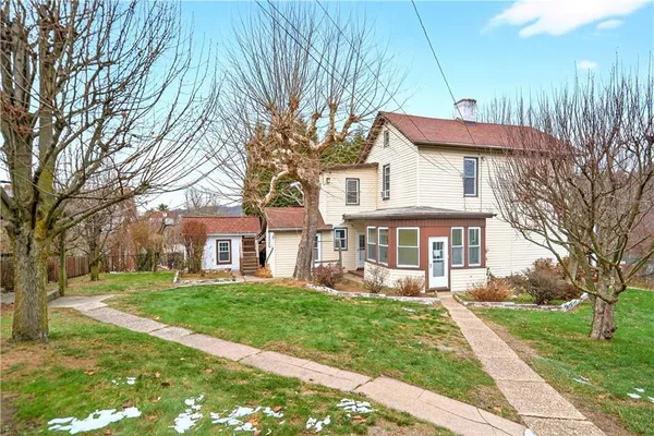 a front view of a house with a garden and trees