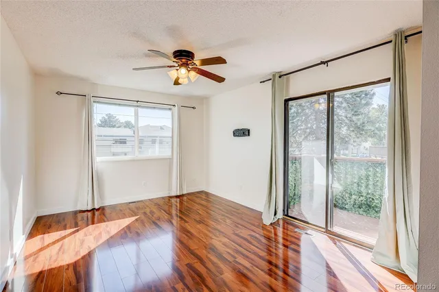 a bedroom with wooden floor a ceiling fan and a window