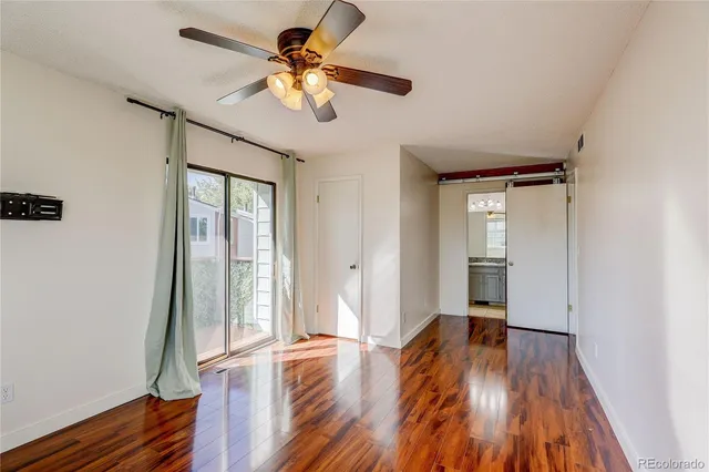 a view of empty room with wooden floor and fan