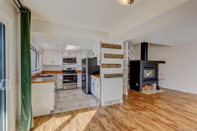 a kitchen view with stainless steel appliances wooden floor and view living room