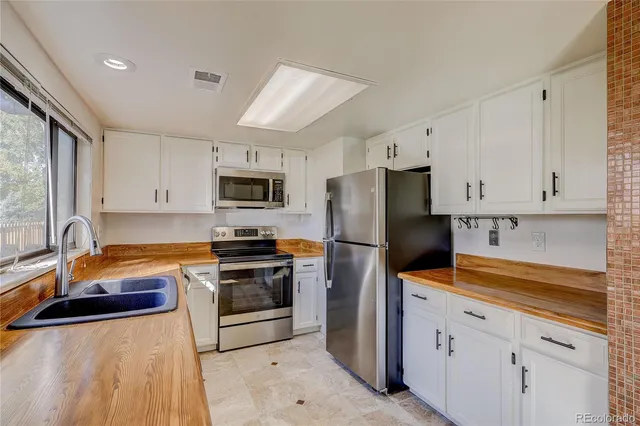 a kitchen with granite countertop a refrigerator stove and sink