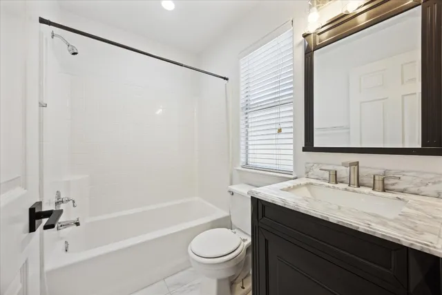 a bathroom with a granite countertop sink a toilet a mirror and shower