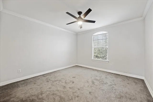 an empty room with ceiling fan and windows