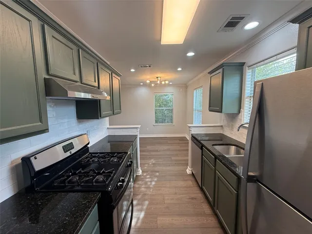 a kitchen with stainless steel appliances granite countertop a stove a sink and a refrigerator