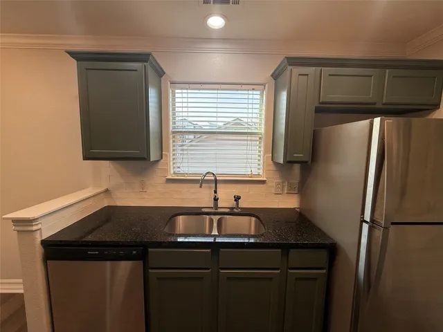 a kitchen with a sink a refrigerator and cabinets