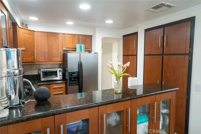 a kitchen with granite countertop a refrigerator a stove and a sink with wooden floor