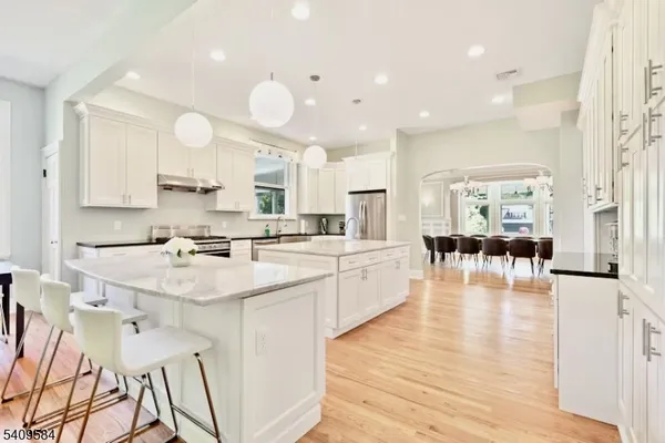 a large white kitchen with lots of counter space wooden floor and appliances