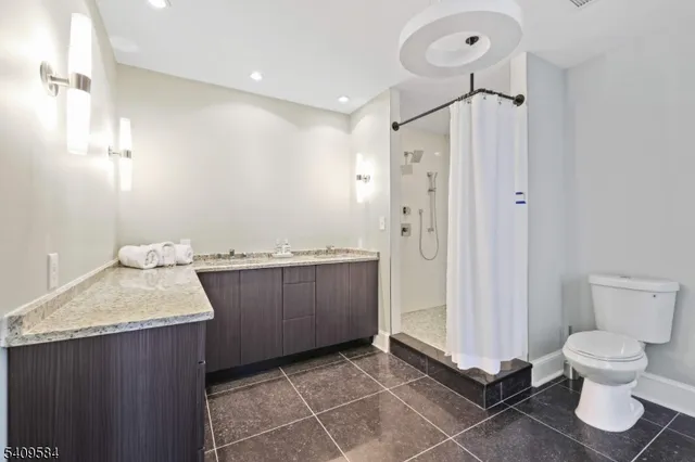 a bathroom with a granite countertop sink a toilet and a shower