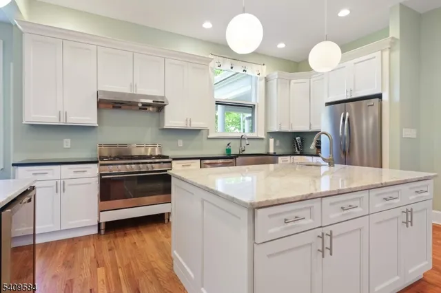 a kitchen with kitchen island granite countertop a sink cabinets and stainless steel appliances