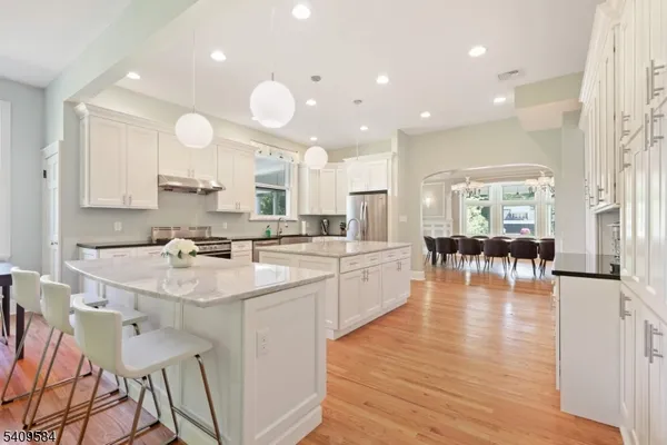 a kitchen with stainless steel appliances granite countertop a stove top oven a sink dishwasher and white cabinets with wooden floor