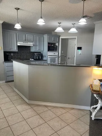 a kitchen with stainless steel appliances granite countertop a refrigerator a sink dishwasher a stove and white cabinets with wooden floor