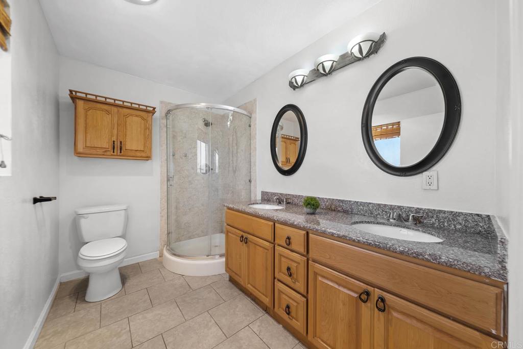 10981 Santa Cruz Road Desert Hot Springs, CA 92240 - Photo 19 of 43 a bathroom with a granite countertop toilet a sink and a mirror