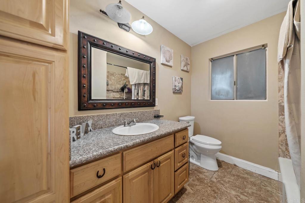 10981 Santa Cruz Road Desert Hot Springs, CA 92240 - Photo 3 of 43 a bathroom with a granite countertop toilet sink and mirror