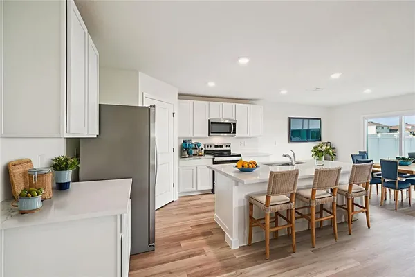 a kitchen with stainless steel appliances a dining table chairs refrigerator and microwave