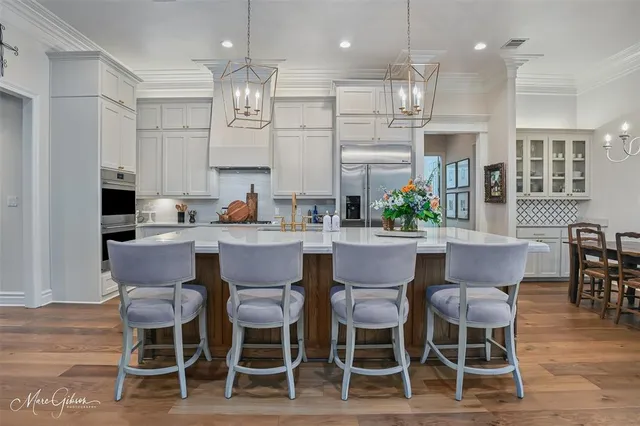 a dining room with stainless steel appliances kitchen island granite countertop a dining table chairs and a refrigerator