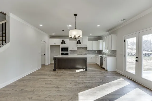 a large kitchen with granite countertop a large counter top a sink stainless steel appliances and cabinets