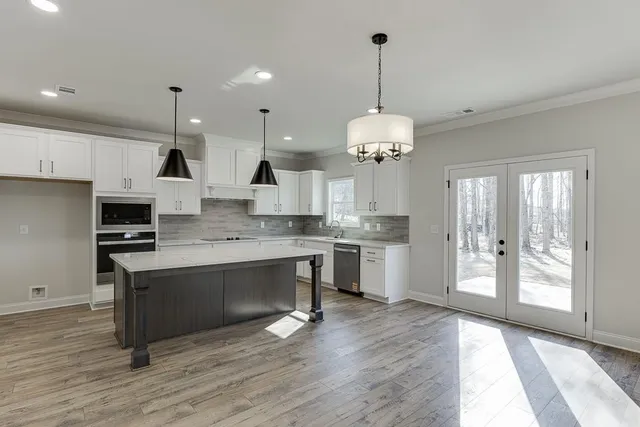 a large kitchen with granite countertop a stove a sink a refrigerator and a wooden floor