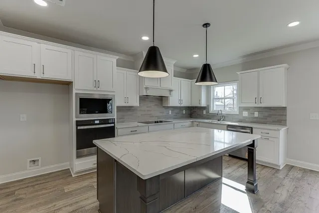 a kitchen with a stove a sink a microwave and wooden floor