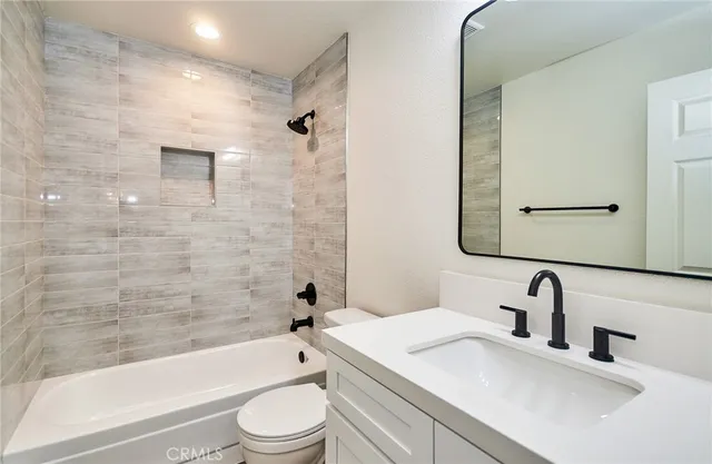 a bathroom with a bathtub shower sink vanity mirror and toilet
