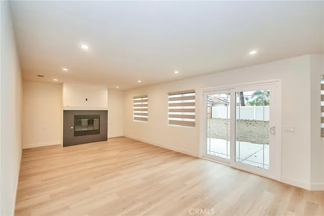 an empty room with floor to ceiling window and wooden floor