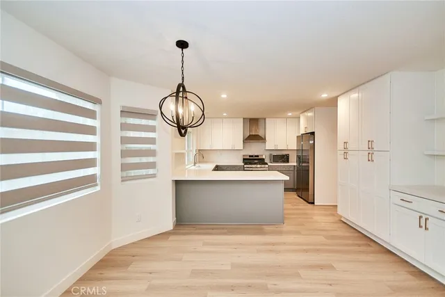 a kitchen with stainless steel appliances a stove a refrigerator and white cabinets with wooden floor