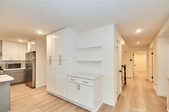 a view of a kitchen with refrigerator and wooden floor