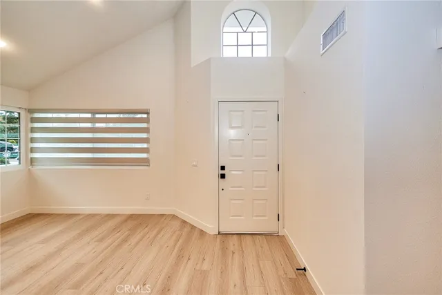 an empty room with wooden floor cabinet and windows