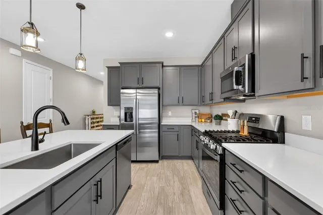 a kitchen with stainless steel appliances a stove a sink and white cabinets