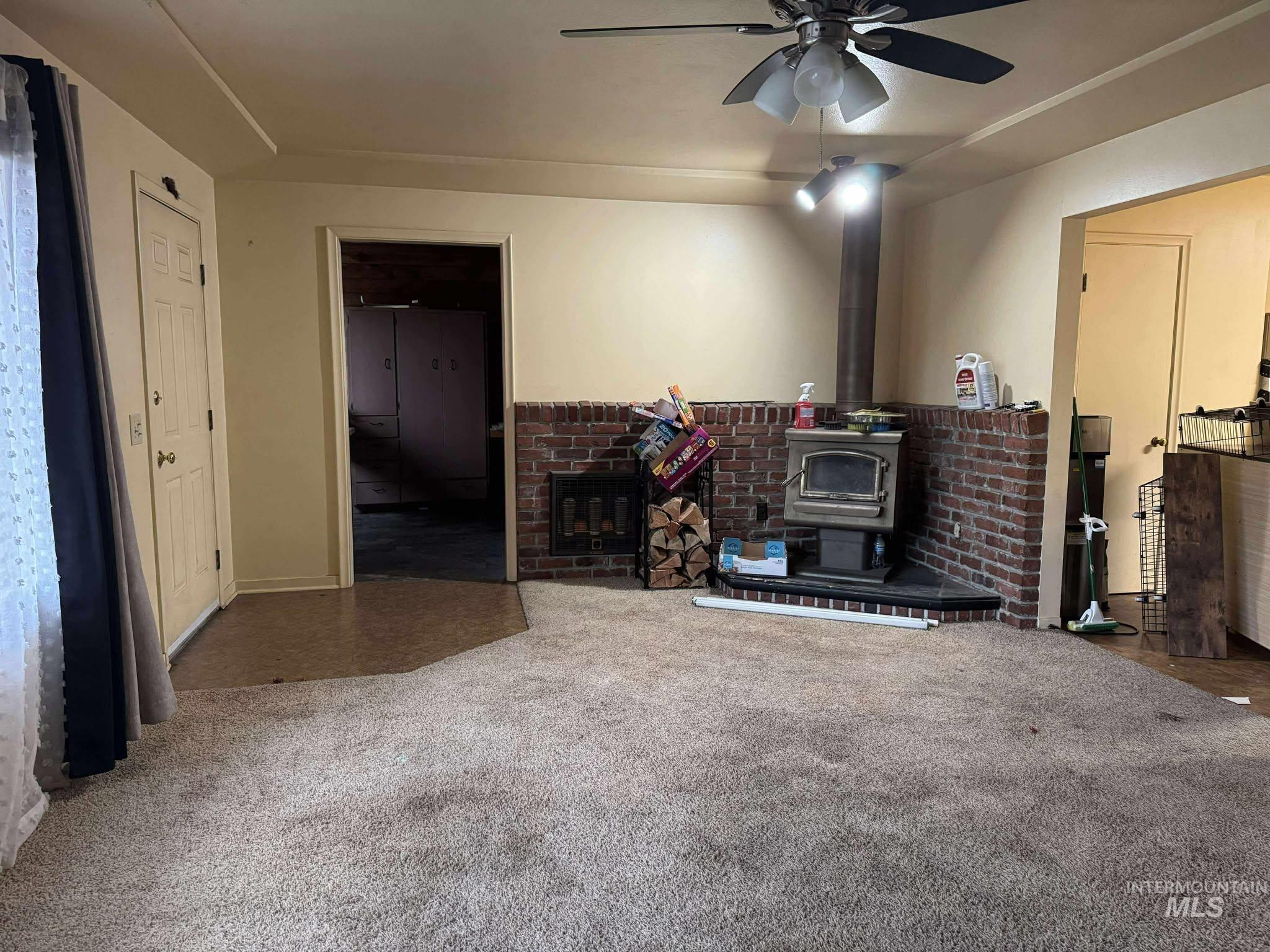 326 7th Street Lapwai, ID 83540 - Photo 2 of 5 Living area featuring a wood stove, carpet flooring, and ceiling fan