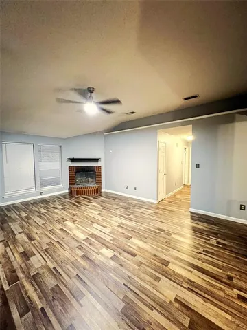 a view of empty room with wooden floor and fireplace