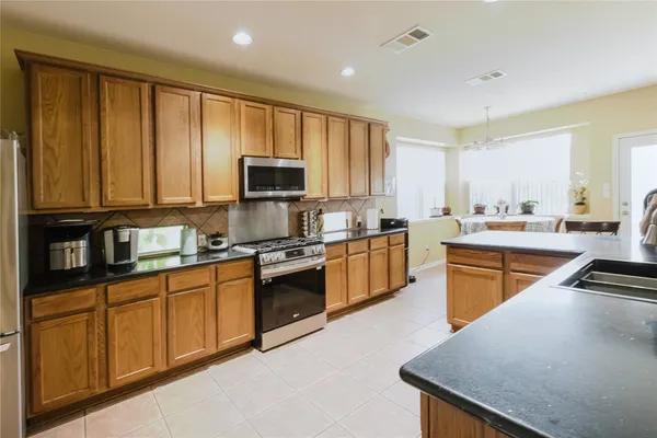 a kitchen with stainless steel appliances granite countertop wooden cabinets a stove top oven a sink and dishwasher