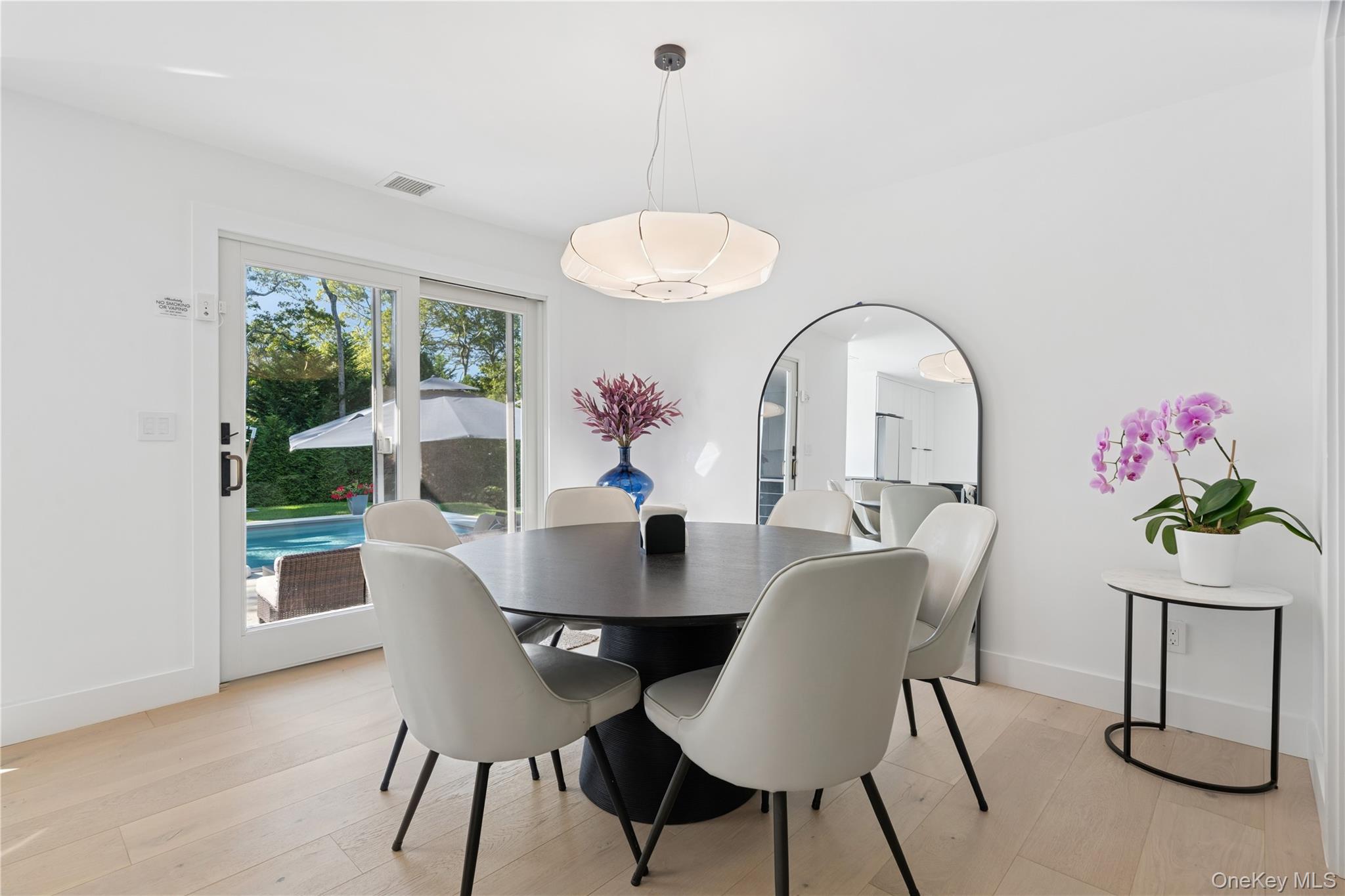 13 Sherwood Road Hampton Bays, NY 11946 - Photo 8 of 27 a dining room with furniture a potted plant and a chandelier