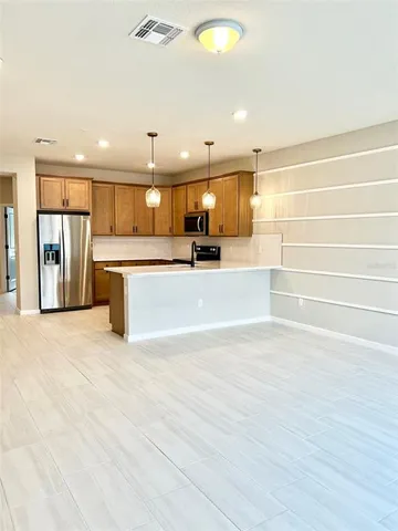 a view of kitchen with stainless steel appliances wooden floor and chandelier