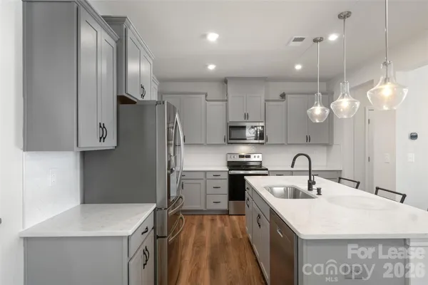 a kitchen with kitchen island granite countertop a sink a stove a refrigerator cabinets and wooden floor