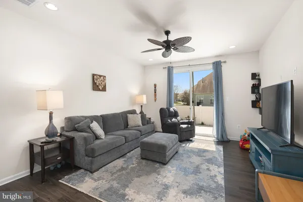 a living room with furniture a ceiling fan and a flat screen tv