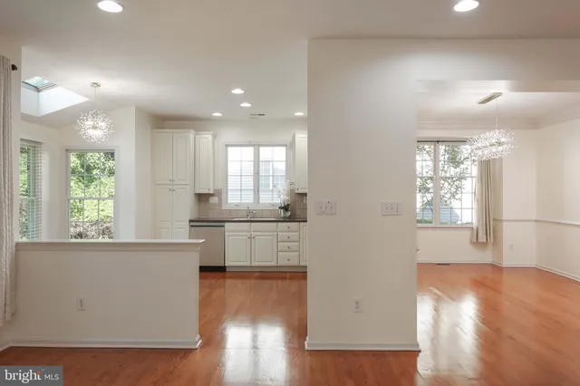 a kitchen with stainless steel appliances granite countertop a refrigerator a sink dishwasher a stove white countertops and wooden floor