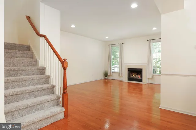 a view of an empty room with wooden floor fireplace and a window