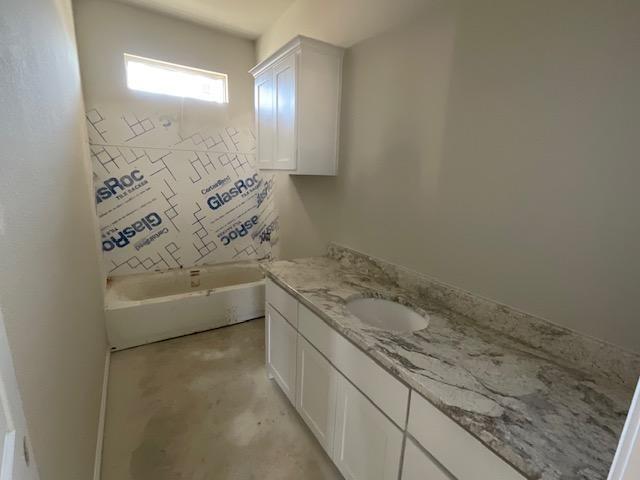 1203 Anthony Street Gainesville, TX 76240 - Photo 18 of 24 a bathroom with a granite countertop bathtub sink vanity and mirror