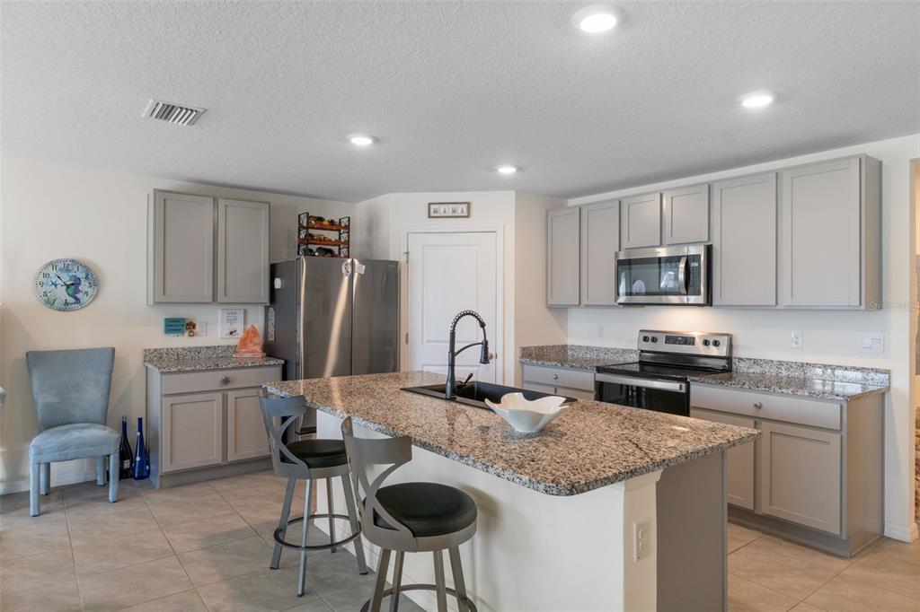 7514 Gardner Street Brooksville, FL 34613 - Photo 12 of 49 a kitchen with stainless steel appliances granite countertop a sink a stove a refrigerator cabinets and chairs