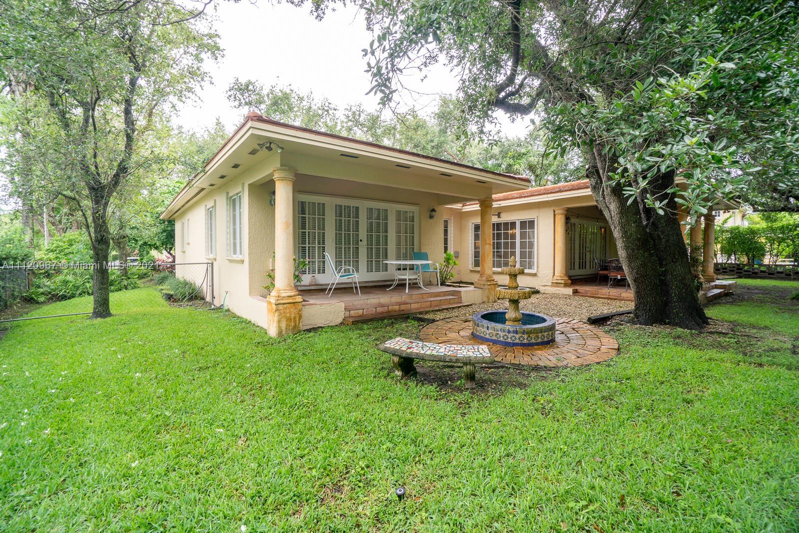 4423 Anderson Road Coral Gables, FL 33146 - Photo 18 of 18 a backyard of a house with table and chairs potted plants and large tree