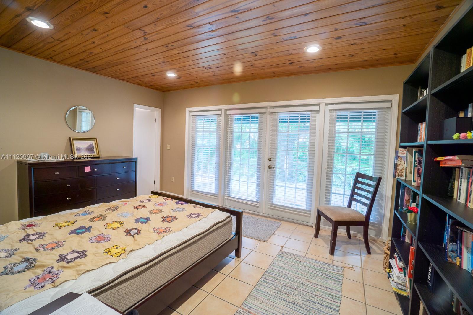4423 Anderson Road Coral Gables, FL 33146 - Photo 10 of 18 a bedroom with a bed a large window and bookshelf