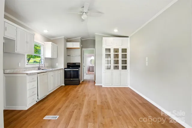 a kitchen with a refrigerator a stove top oven a sink and dishwasher with wooden floor