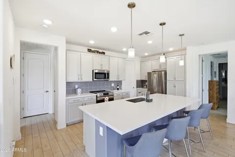 a kitchen with stainless steel appliances a stove a sink a refrigerator a center island a dining table and chairs
